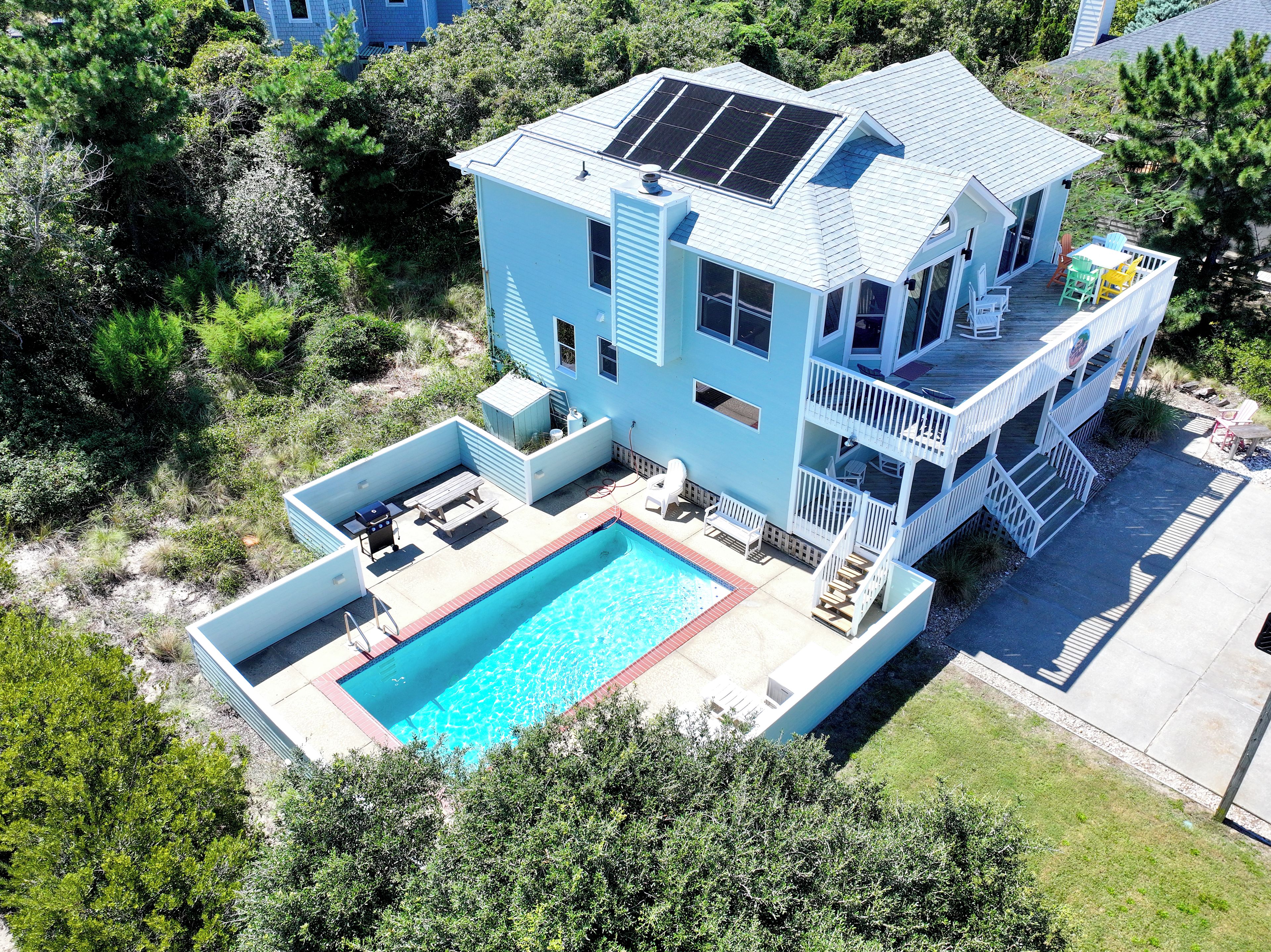 A two-story house with a swimming pool, solar panels, and a deck.
