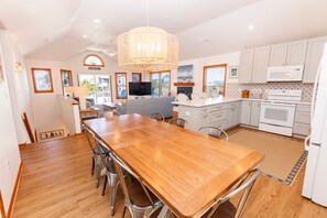 A spacious kitchen with a wooden dining table, white cabinets, and a large island. - Oceanside- Private Pool, Hot Tub-SG113, Sandy Peach (Duck)