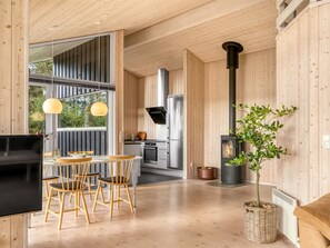 A modern kitchen with wooden walls, a central island, and a black stove. - "Chris" - 130m from the sea by Interhome (Hals)