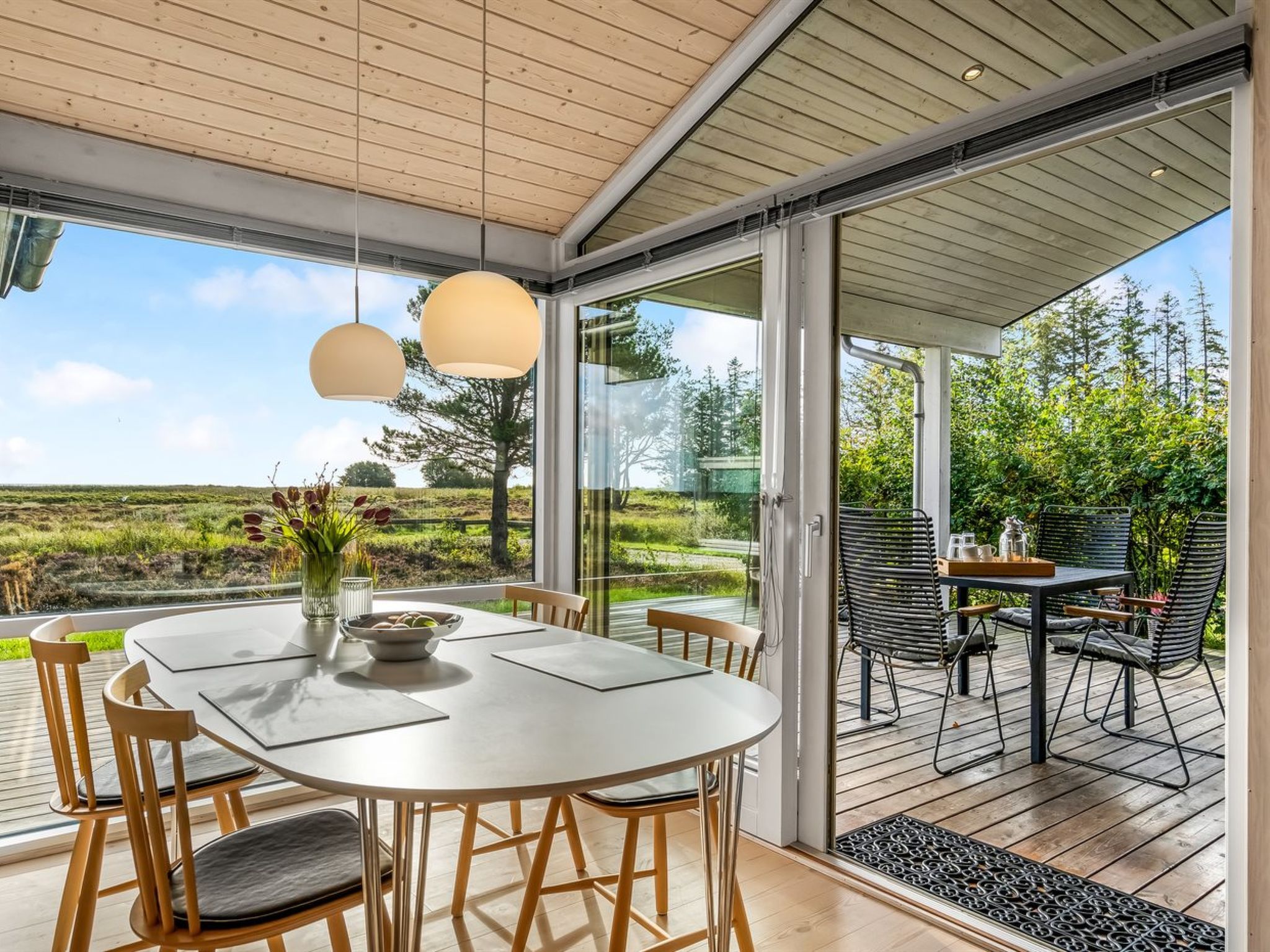 A modern dining area with a round table and chairs, large windows, and a view of the outdoors.