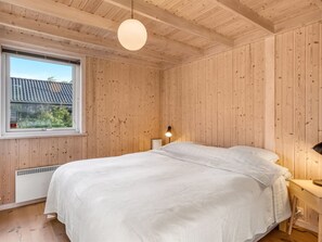 A bedroom with a large bed, wooden walls, a window, and a hanging light fixture. - "Chris" - 130m from the sea by Interhome (Hals)