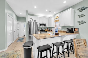 A modern kitchen with white cabinets, stainless steel appliances, and a granite countertop. - Pineapple Under the Sea– Great Florida Cottage Near 30A Beaches (Santa Rosa Beach)