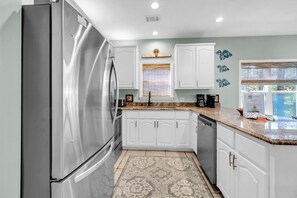 A modern kitchen with stainless steel appliances, white cabinetry, and a patterned rug. - Pineapple Under the Sea– Great Florida Cottage Near 30A Beaches (Santa Rosa Beach)