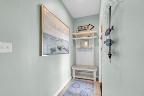 A hallway with a painting of boats on water, a shelf with a 'BEACH' sign, and a bench. - Pineapple Under the Sea– Great Florida Cottage Near 30A Beaches (Santa Rosa Beach)