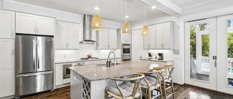 Een moderne keuken met een centraal eiland, roestvrijstalen apparatuur en uitzicht op de omgeving.