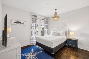 A bedroom with a bed, bedside tables, a television, and a chandelier. - 🐚 Gone Coastal | Private Heated Pool + Hot Tub | Bikes | Fire Pit (Santa Rosa Beach)