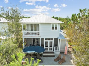 A two-story house with a balcony, a covered patio, and a front porch with seating. - 🐚 Gone Coastal | Private Heated Pool + Hot Tub | Bikes | Fire Pit (Santa Rosa Beach)