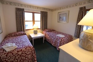 A hotel room with two single beds, a small table, a lamp, and a window with curtains. - Deer Park 2 Bedroom with near Loon Mountain! (Woodstock)