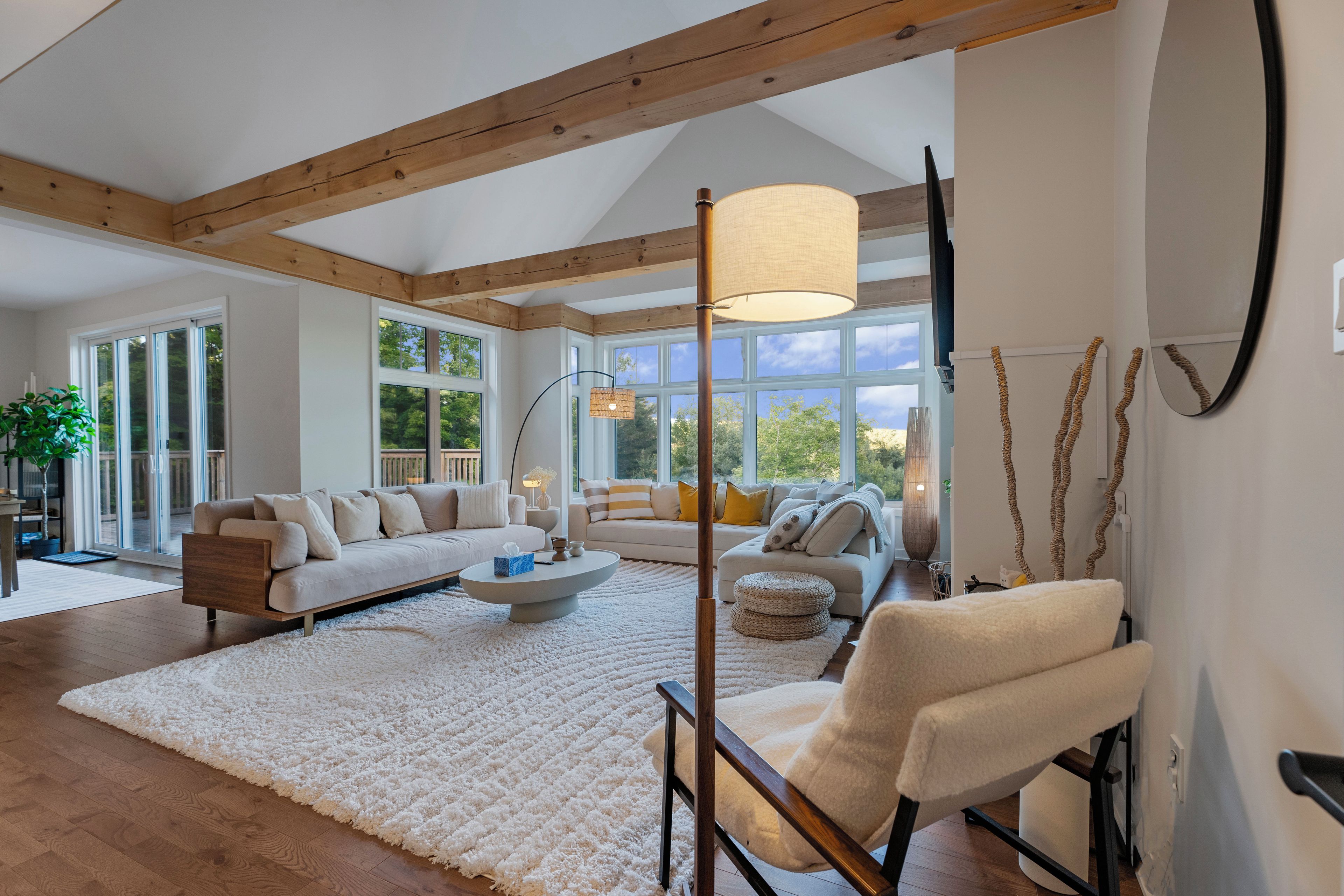 A spacious living room with a large window, a sofa, a coffee table, and a chair.