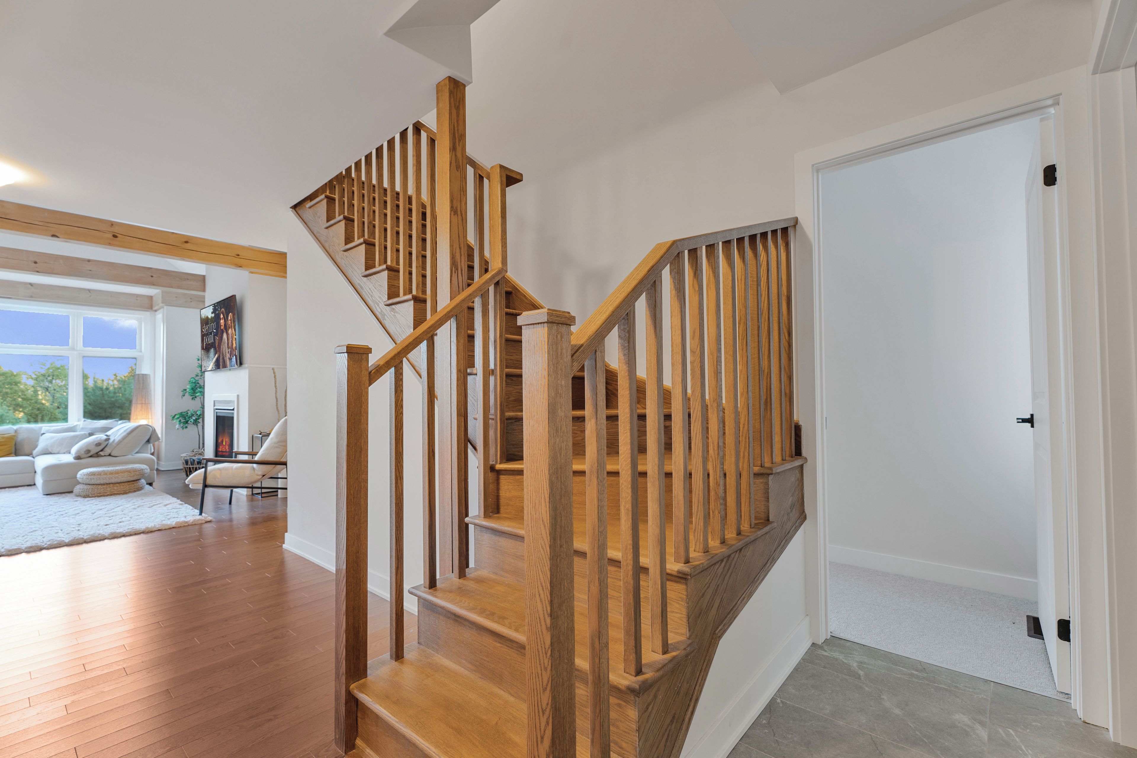 Un escalier en bois avec une rampe, menant à une porte blanche.