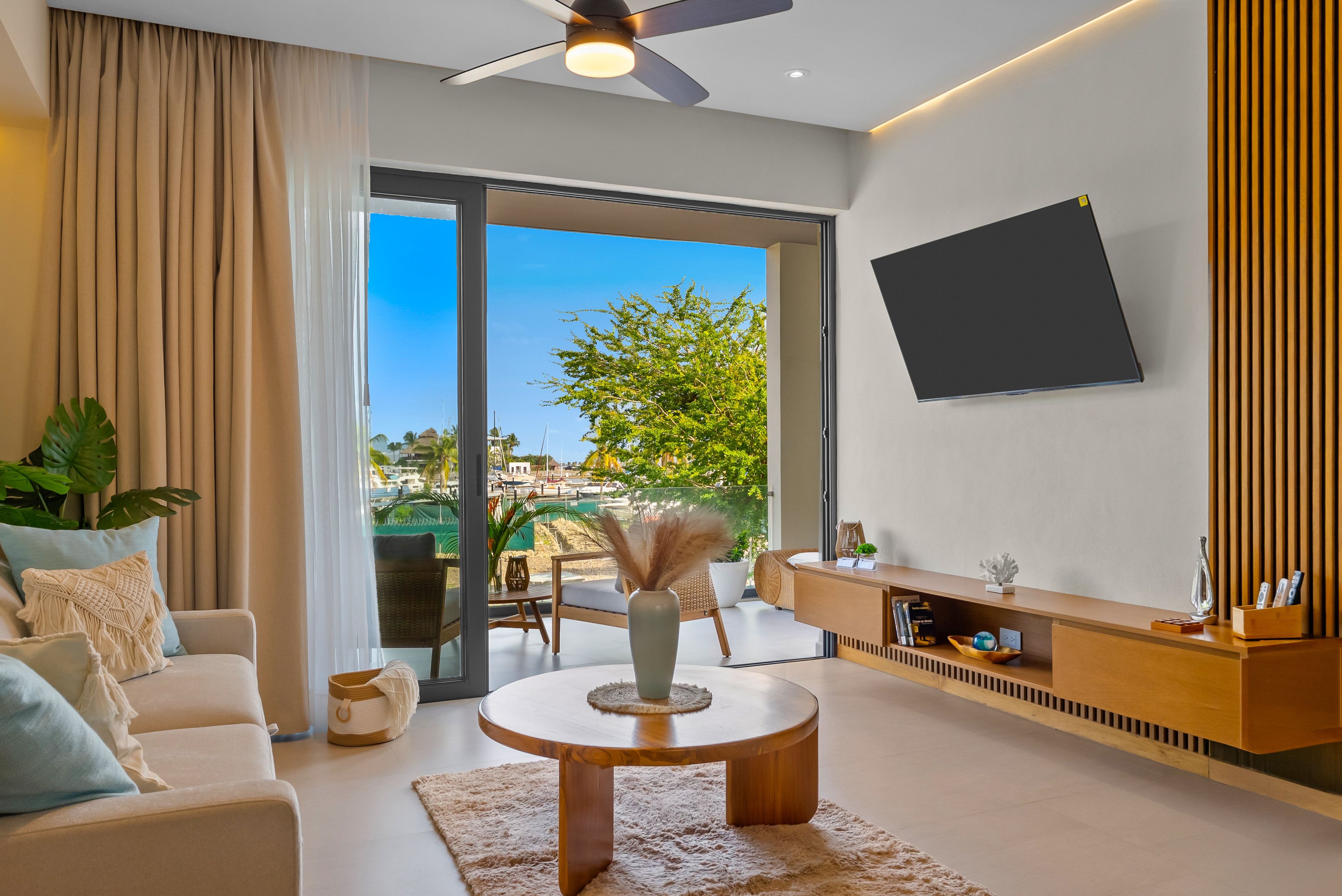 A modern living room with a sofa, coffee table, and a flat-screen TV mounted on the wall.