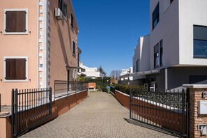 A residential street with a paved walkway, metal gates, and buildings with balconies and windows. - Villa Leon (Istria - Funtana) (Funtana)