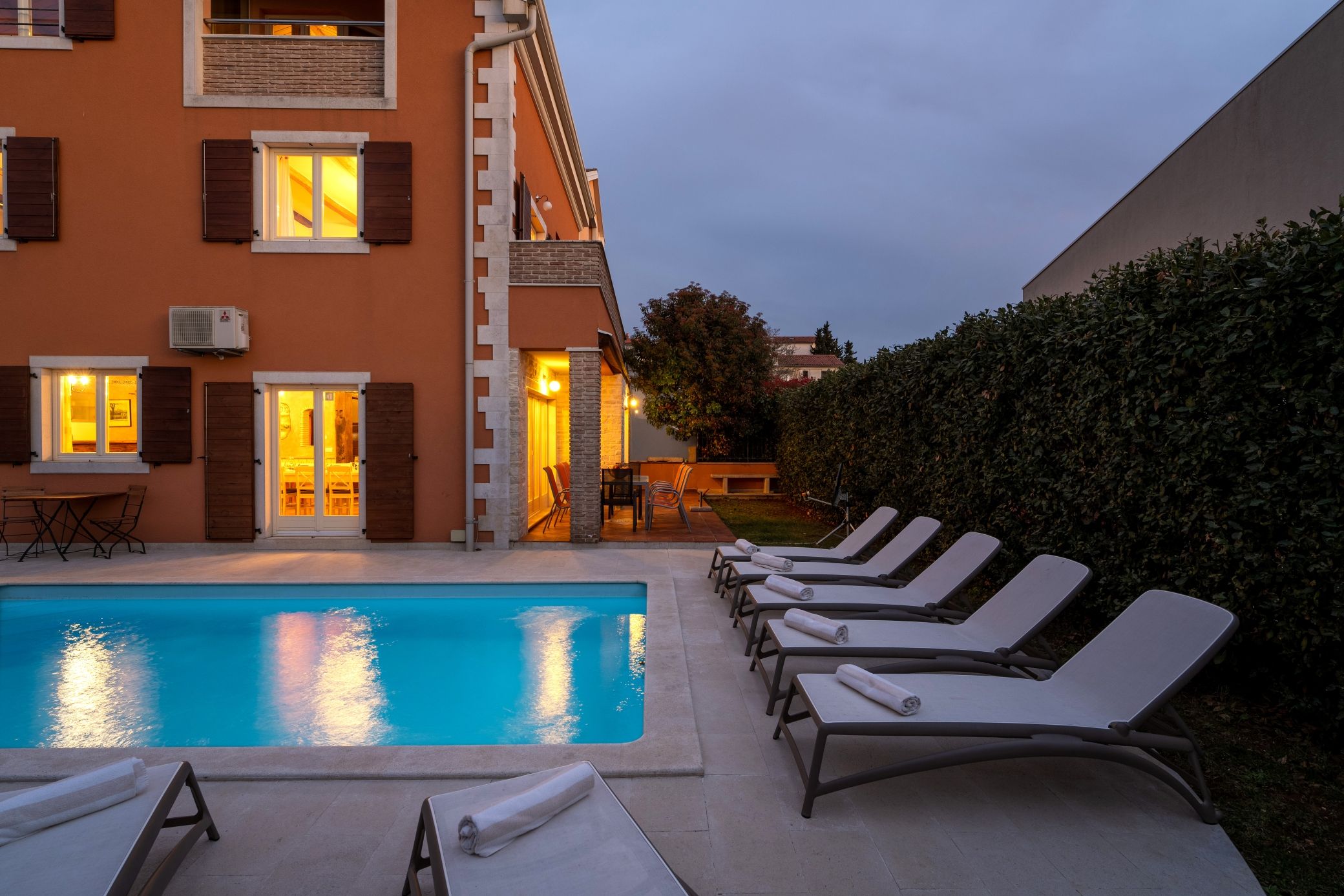 A poolside area with lounge chairs and a building with a brick facade.