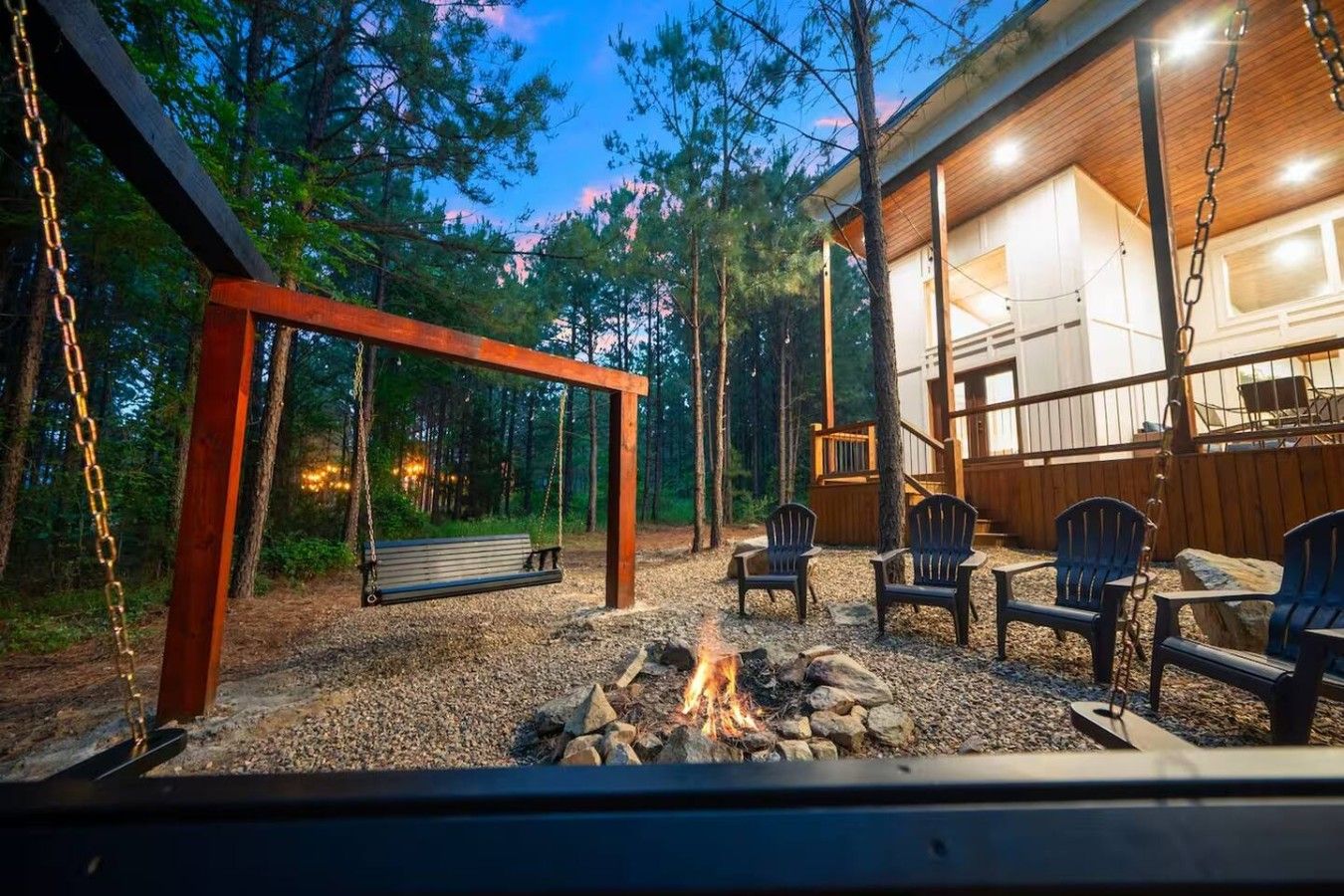 Un ensemble de jeux d’extérieur en bois avec balançoire, un foyer et des sièges extérieurs avec des chaises.