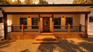 Een gebouw met een overdekte veranda, houten leuningwerken en een grindpad.