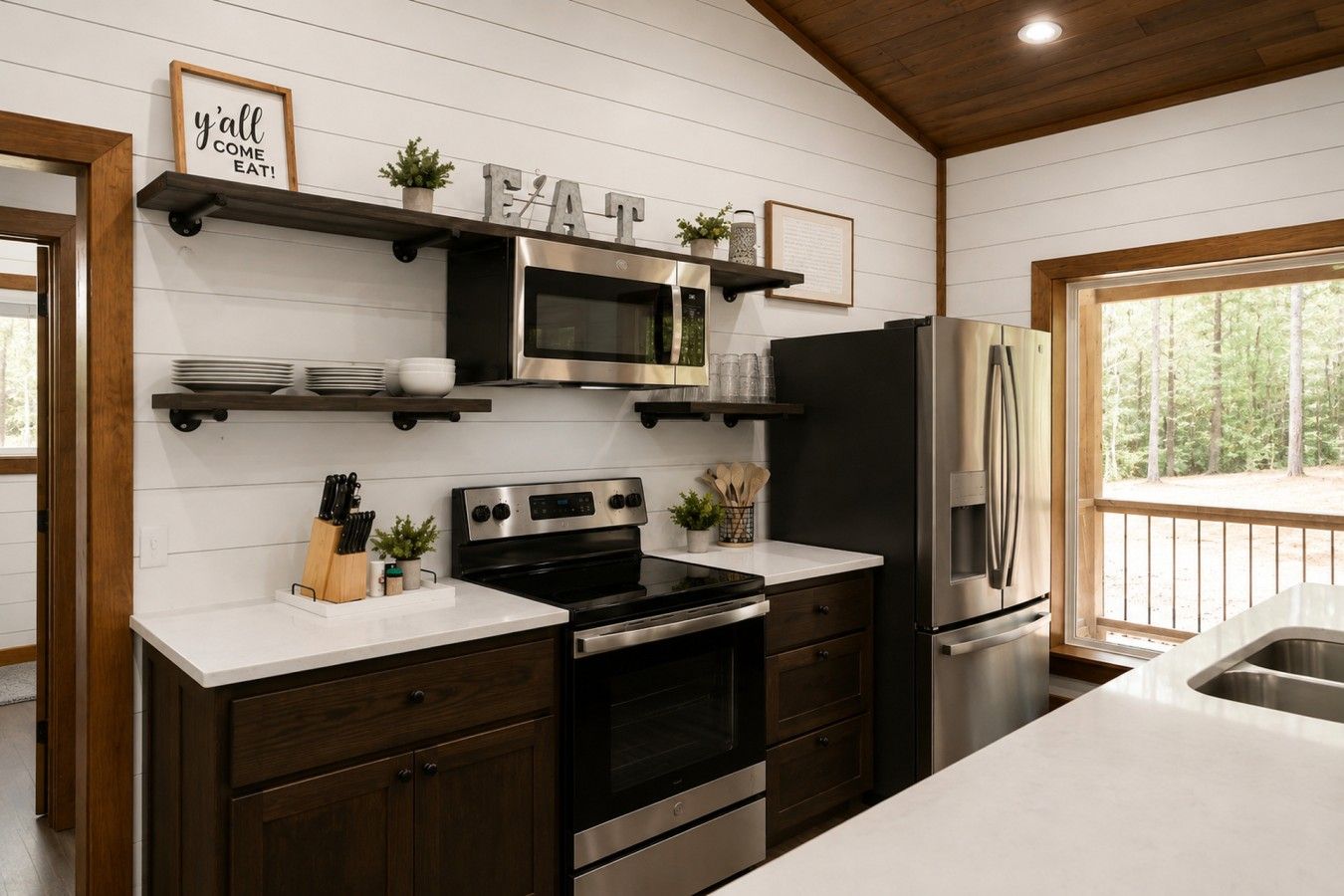 A modern kitchen with white cabinetry, stainless steel appliances, and a view of the outdoors.