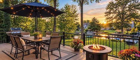 An outdoor deck with a grill, dining table, chairs, and a fire pit.
