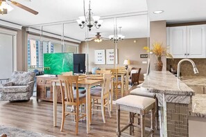 A modern kitchen with a marble countertop, wooden chairs, and a dining area with a large table. - Gulf View Condo | Pool | Sleeps 6 (Destin)