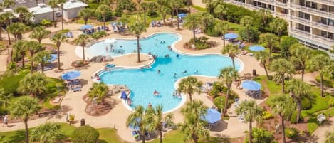 Um resort com várias piscinas, palmeiras e um edifício grande com varandas.