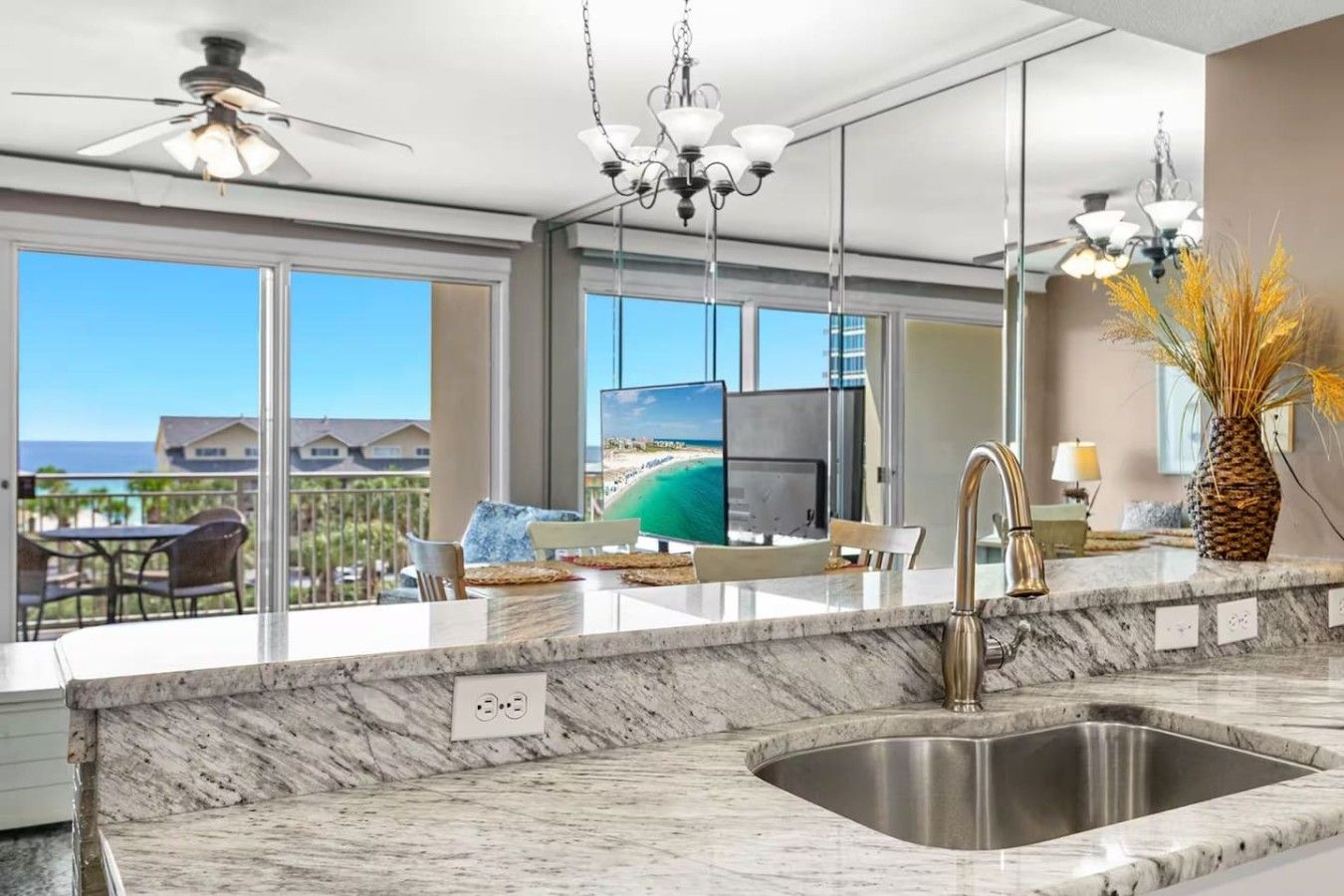 A modern kitchen with a large island, a built-in TV, and a view of the ocean.