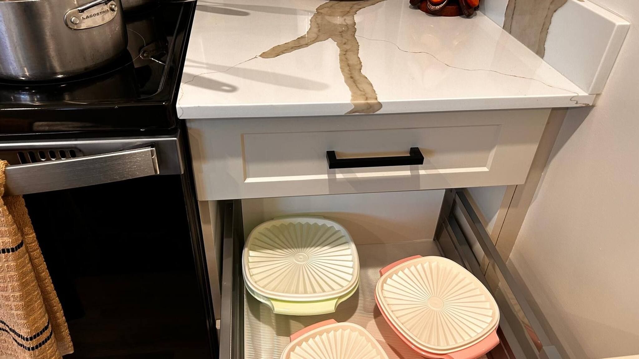 A kitchen with a stove, a white countertop, and a drawer with a handle.