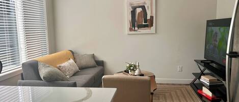 A living room with a sofa, a coffee table, a television, and a painting on the wall.