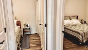 A hotel room with a bed, bedside table, lamp, and a small rug. - Brighton Escape, Spacious 2BR Walk-out Suite (Saskatoon)