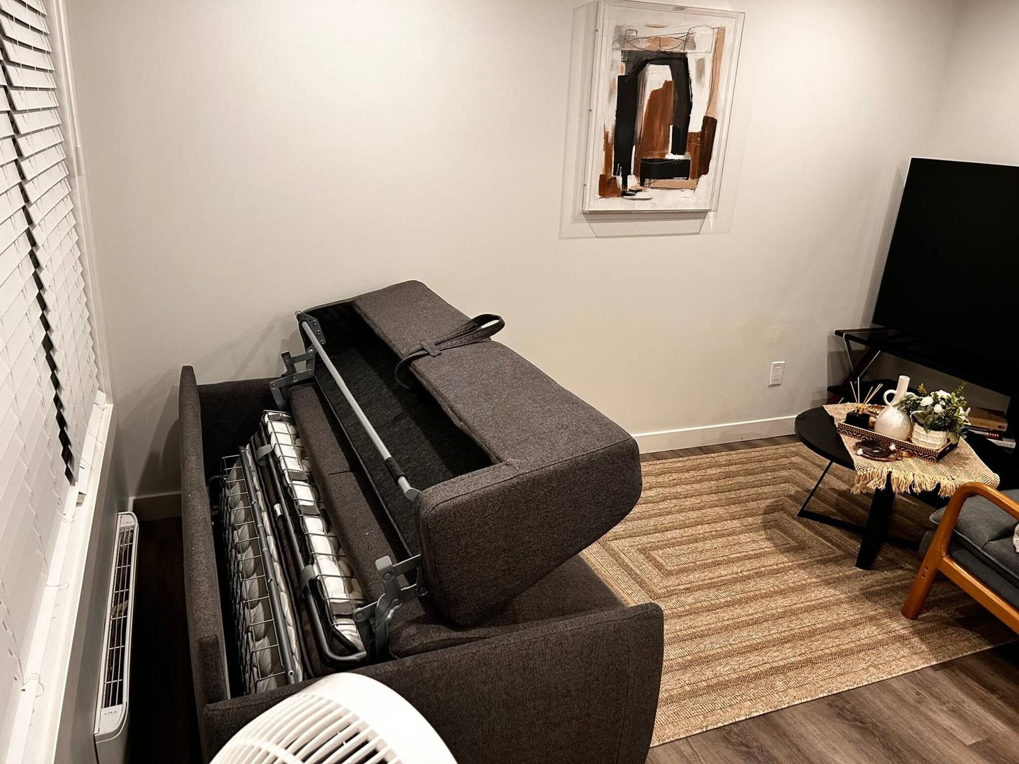A room with a piano, a television, and a small table with decorative items.