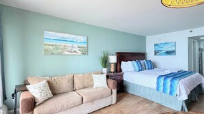 Une chambre à coucher avec un lit, une table de chevet, une lampe, une plante en pot et un tableau accroché au mur.