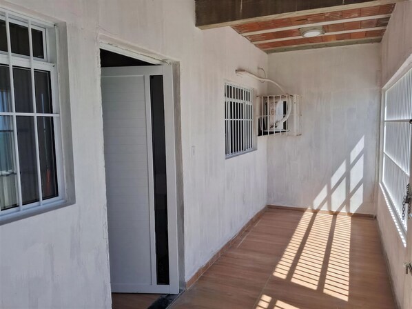 A hallway with a wooden floor, white walls, and a door leading to another room.
