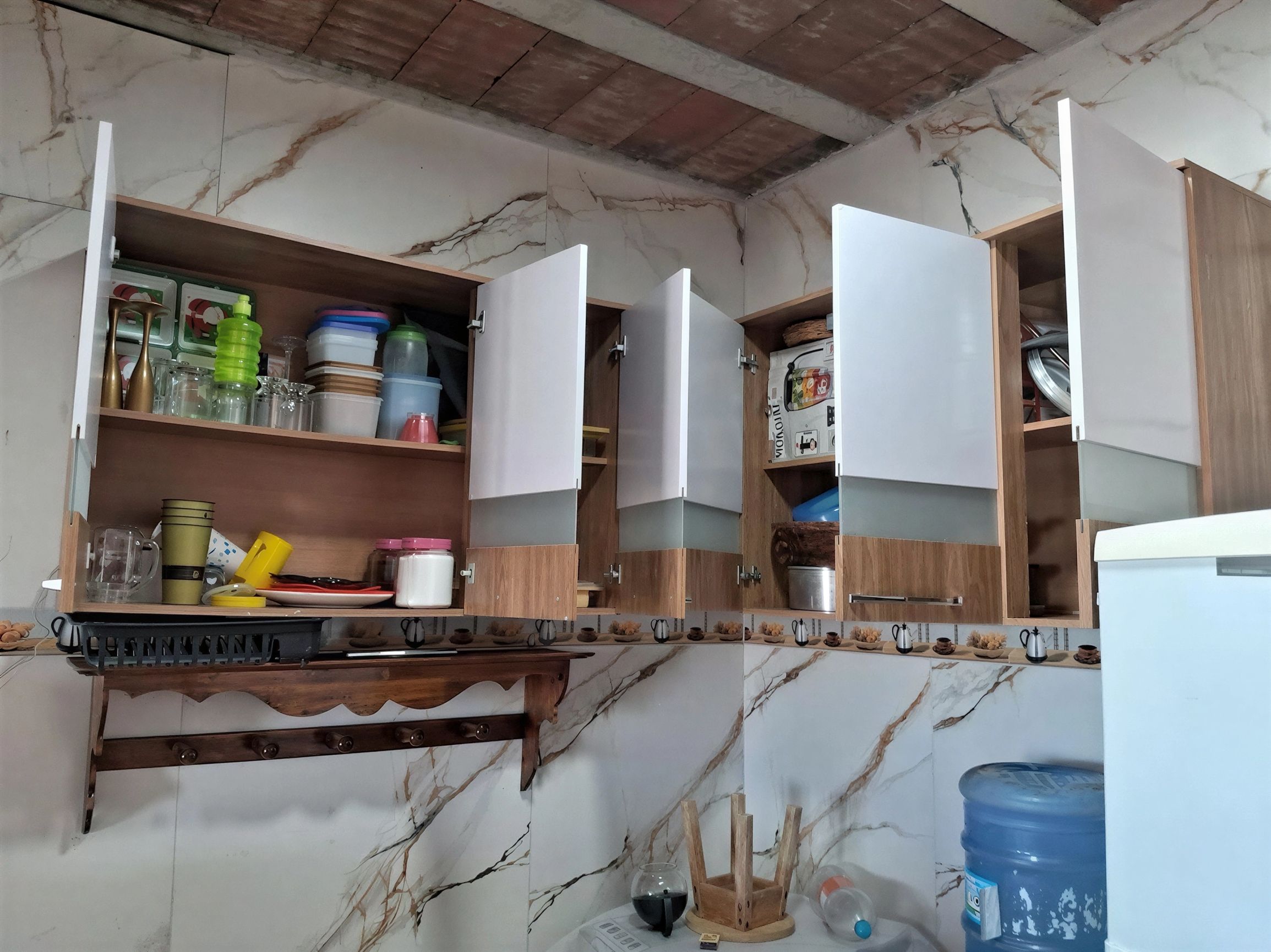 Eine Küche mit Marmorarbeitsplatten, Holzschränken und einem Wasserspender.