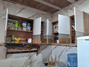 A kitchen with marble countertops, wooden cabinets, and a water dispenser.