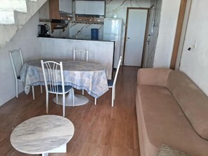 A living room with a round marble table, a beige sofa, and a dining area with a table and chairs. - Beachfront house - Relaxing on the beach (Paulista)