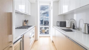 A modern kitchen with white cabinetry, a stove, a microwave, and a sink.