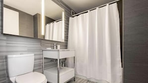 A modern bathroom with a toilet, vanity, and shower curtain.