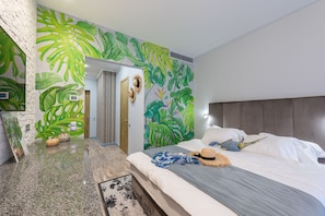 Ein modernes Schlafzimmer mit einem großen Bett, einer Kopfteil und einem Wandbild mit tropischen Blättern.