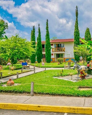 Un hotel con un patio central, rodeado de follaje y árboles altos.