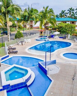 A resort with multiple swimming pools, palm trees, and lounge chairs.