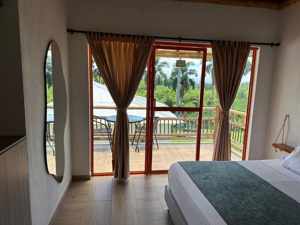 Un dormitorio con una cama grande, vistas a un balcón con mesa y sillas, y una puerta corrediza de vidrio.