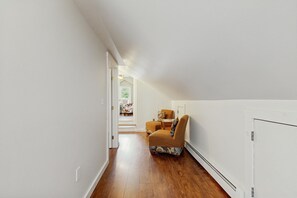 A narrow hallway with wooden flooring leading to a room with a bed and a chair. - Home on 1.5 private acres with fenced yard, pool table and deck near Pico (Rutland)