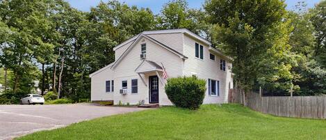 A two-story house with a front porch, a small front yard, and a wooden fence.