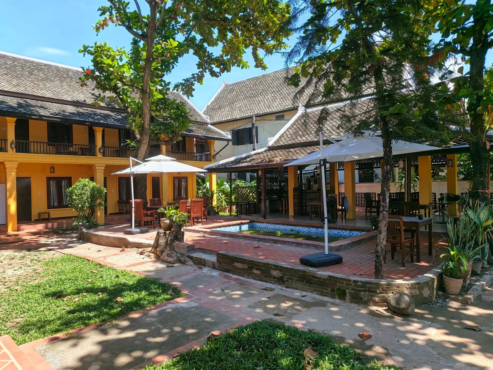 A courtyard with outdoor seating, a pool, and a covered area with umbrellas.