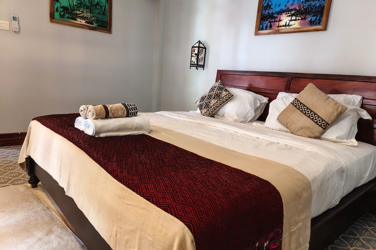 Una habitación de hotel con una cama grande, un cabecero de madera y dos cuadros colgados en la pared.