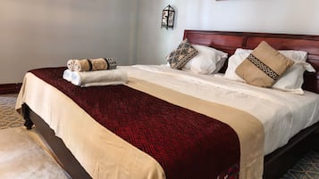 Una habitación de hotel con una cama grande, un cabecero de madera y dos cuadros colgados en la pared.