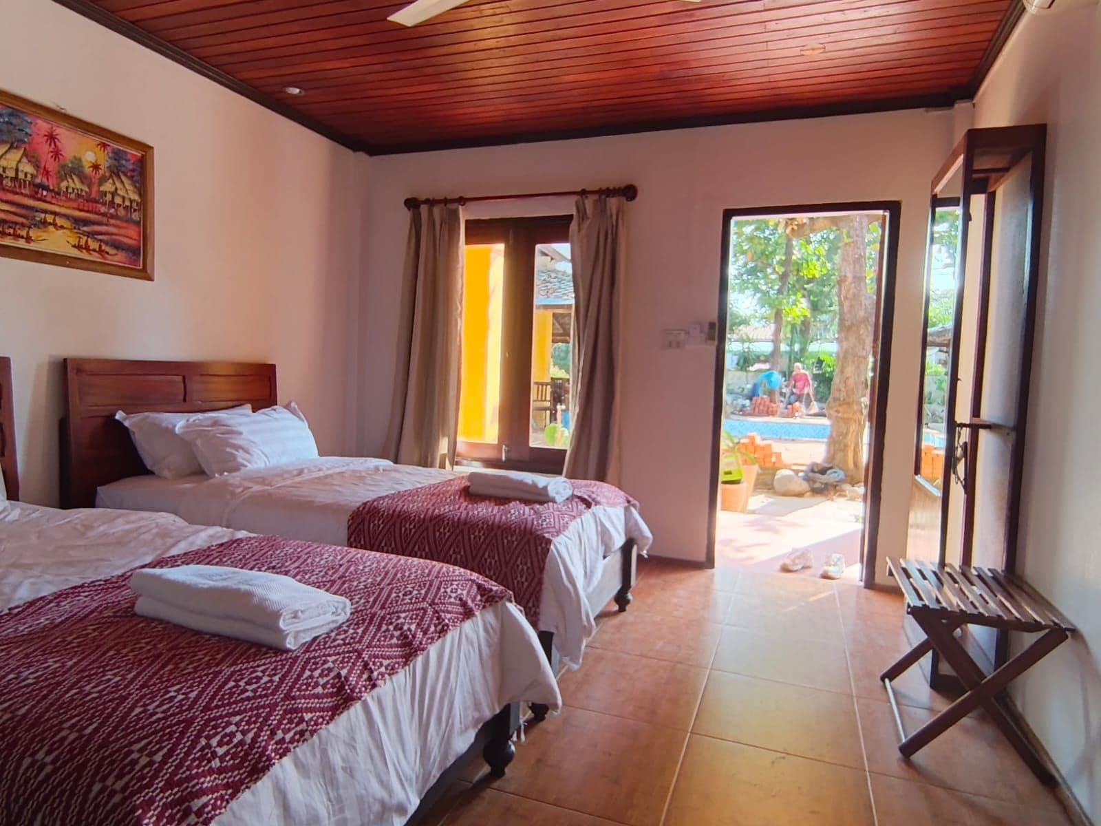 Habitación de hotel con dos camas, techo de madera, un cuadro en la pared y vistas al exterior.