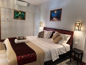Une chambre d’hôtel avec un lit, deux lampes de chevet fixées au mur et deux tableaux.
