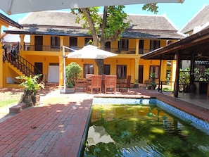 Un patio con piscina, mobiliario exterior y una escalera que lleva a un balcón.