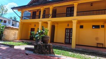 A two-story building with a yellow facade, multiple windows, and a balcony.