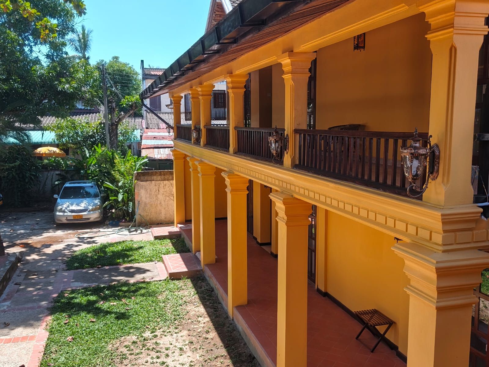 A yellow building with a covered walkway and a car parked outside.