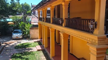 A yellow building with a covered walkway and a car parked outside.